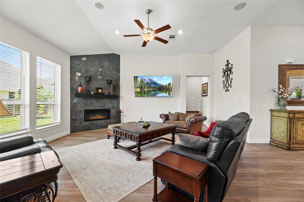 Sweeping views of the outdoors paired with the ambient glow of the fireplace create a serene and inviting atmosphere, perfect for both relaxation and entertaining.