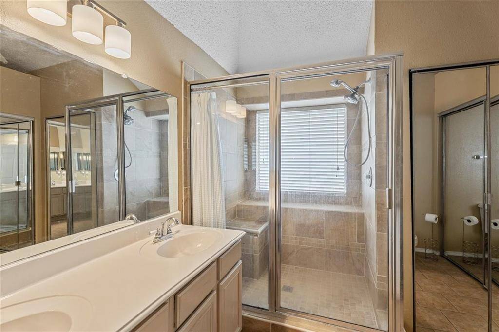 The primary bath features double sinks and a spacious walk-in shower, offering both comfort and convenience.