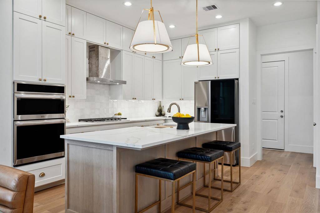 Floor-to-ceiling cabinetry, sleek double ovens, and a generous island set the tone for effortless entertaining.
