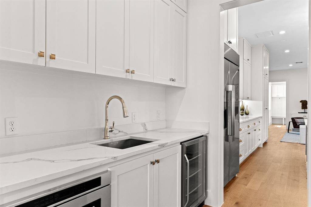 A seamless connection between kitchen and dining—this butler’s pantry is outfitted with quartz countertops, glass-front wine fridge, and polished brass hardware for the ultimate entertaining hub.
