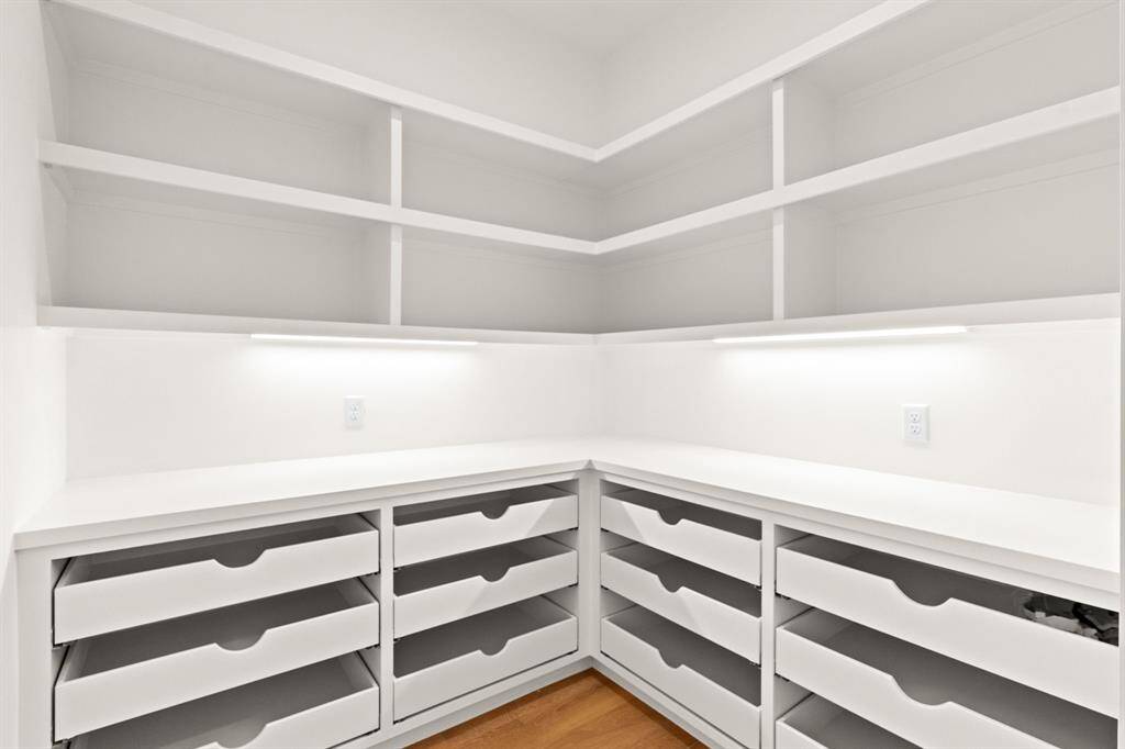 A true storage dream—this custom walk-in pantry offers abundant shelving, deep drawers, and sleek under-cabinet lighting to keep everything organized and beautifully displayed.
