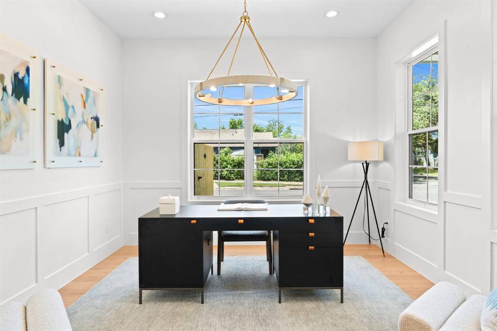 A front-facing study with timeless wainscoting, large windows, and stylish lighting.