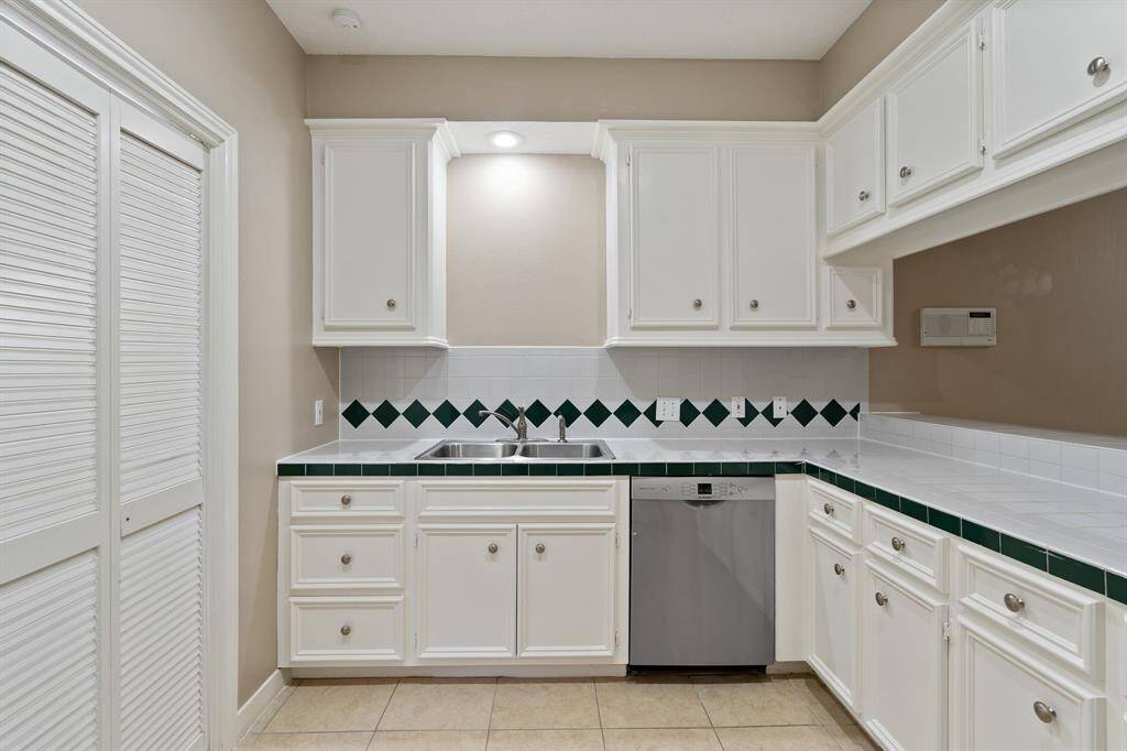 CHARMING and roomy kitchen with beautiful white cabinets and tile countertops.