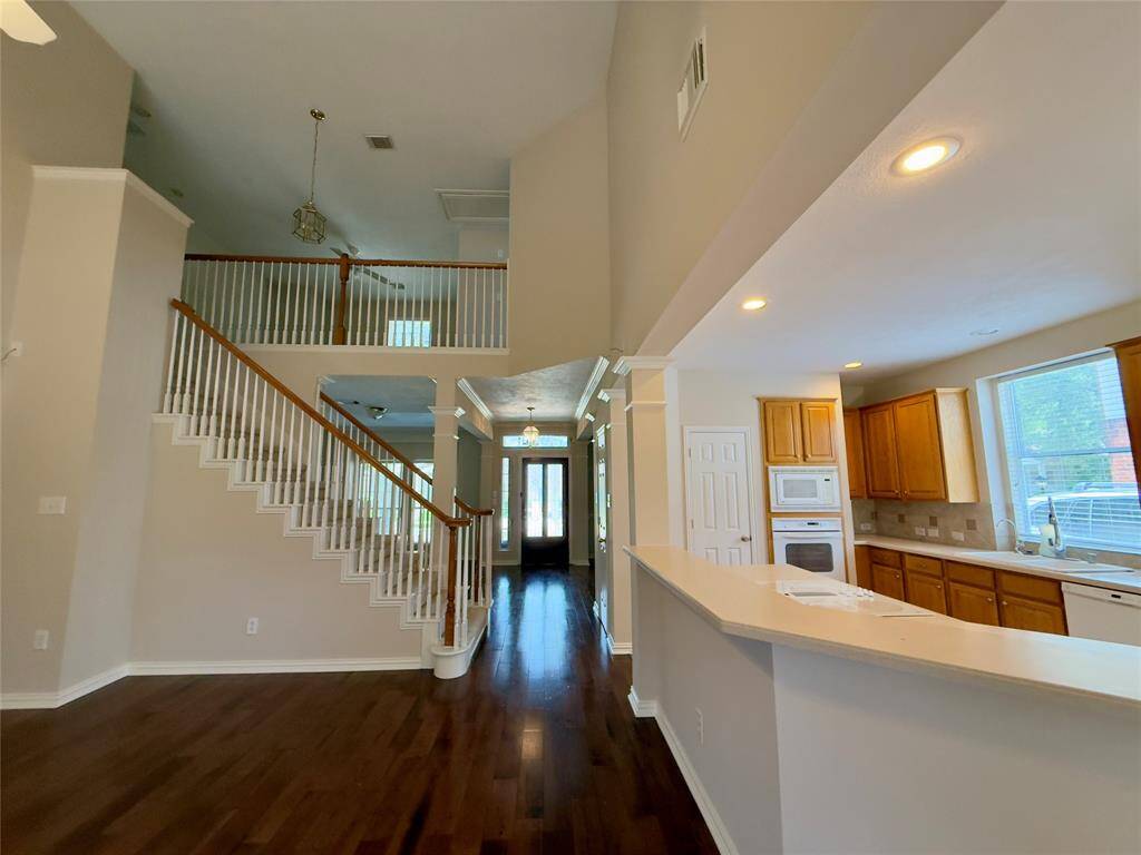 This spacious home features an open-concept design with a grand staircase and high ceilings. The kitchen includes ample natural light, wooden cabinetry, and a breakfast bar. Hardwood floors add elegance, and the layout is ideal for both entertaining and everyday living.