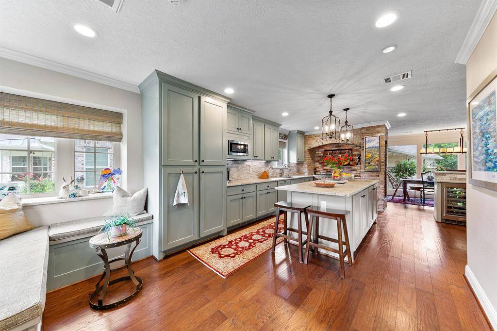 Kitchen island is a beautiful workhorse with open, French-inspired pendant lighting, extra seating and a source of additional storage.