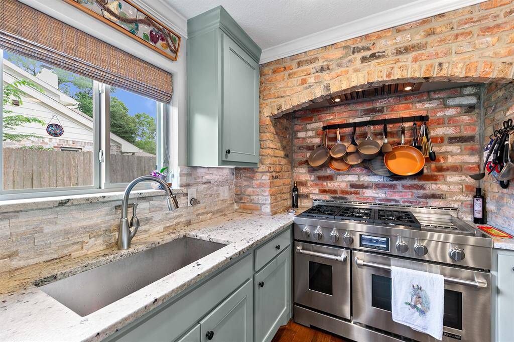 Kitchenaid 6 burner gas range with griddle is tucked into a brick arched-surround which cleverly houses the venting.