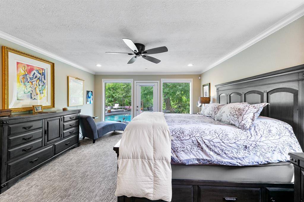 Nature serves as the focal point from this primary bedroom. Sellers embraced the surrounding woods and greenery with the addition of the large framed windows and glass door.
