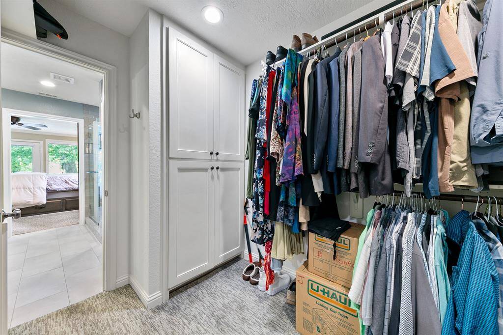 Large walk-in primary closet with cabinetry.