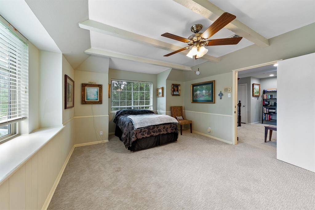 Another view of the guest bedroom showing 2 large windows, beams and ceiling fan.