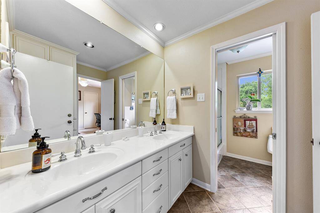 Second story bathroom with two sinks, with separated area housing the bathtub and toilet.