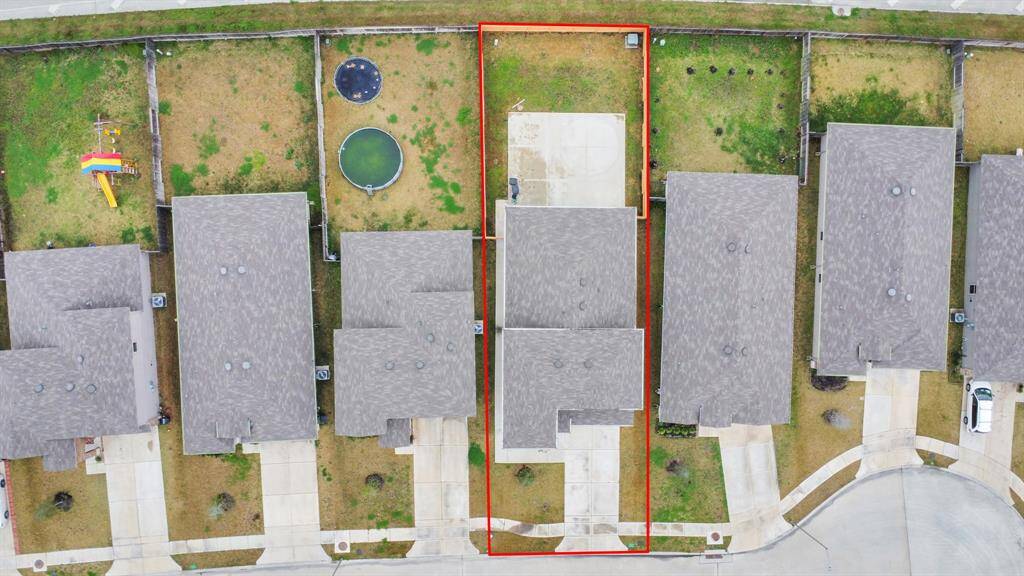 This aerial photo shows a suburban neighborhood with single-family homes. The highlighted property features a fenced backyard with an extended concrete patio area. The lot is rectangular and in a cul-de-sac, offering a private setting.