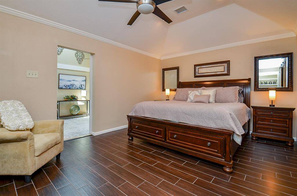 Large primary bedroom is adjacent to the study. Rich, plank, tile flooring, high ceiling with a modern fan and a well-lit reading nook is so inviting.