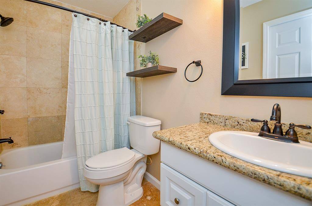The second full  bathroom features a modern design with a granite countertop, sleek black fixtures, and a white vanity. It includes a bathtub with a tiled shower area.