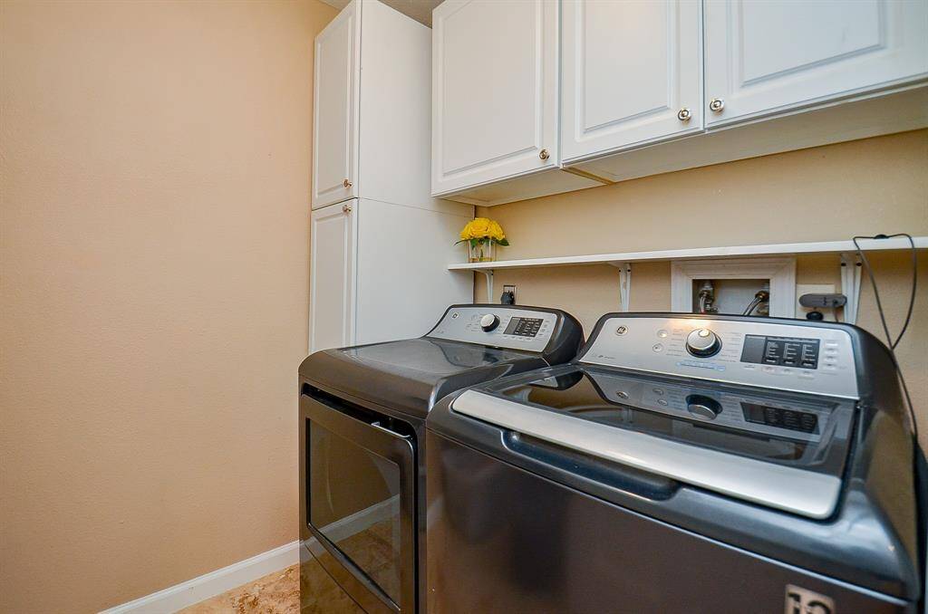 Utility room features space for a modern washer and dryer with overhead cabinetry for storage. The space is bright and functional, offering a clean and organized area for laundry tasks.
