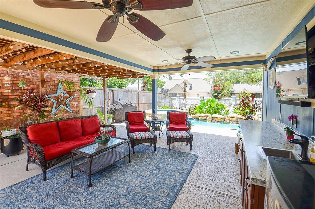 This inviting outdoor space features a covered patio with ceiling fans. Ideal for comfortable seating and wired for an outside television. Great area for entertaining.