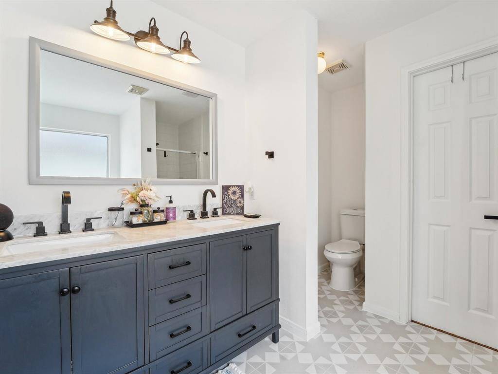 This gorgeous Primary Bathroom is updated with new cabinetry and counters, a pretty framed mirror, and cool tile flooring.