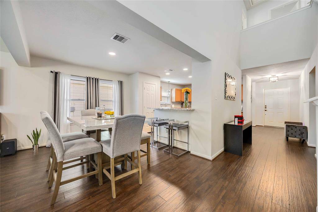 This inviting home features an open-concept layout with a bright dining area, modern kitchen with a breakfast bar, and elegant hardwood floors. High ceilings and large windows enhance the spacious feel, while the entryway offers a warm welcome.