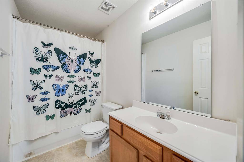 Bright, clean bathroom featuring a large mirror, wooden vanity, and a butterfly-themed shower curtain.