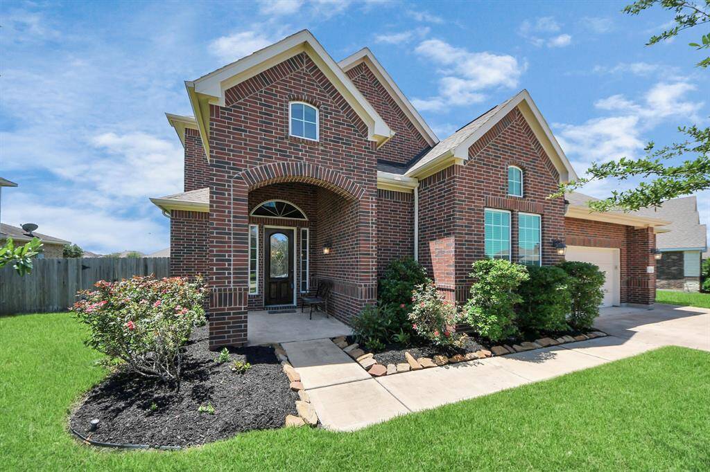 This charming home features a brick exterior with elegant arched entryway, well-maintained landscaping, and a spacious driveway, offering great curb appeal in a serene neighborhood.