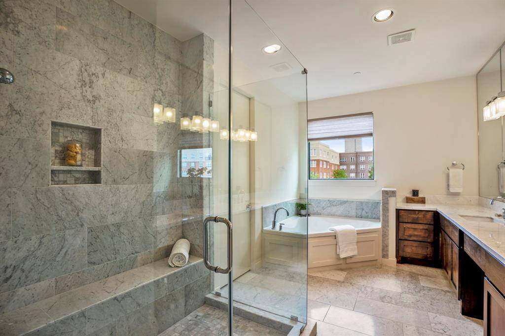 Modern style and design is what you will find in this magnificent spa-like master bath draped in Marrazi Porcelain tile flooring with his and her vanities boasting Carrera marble counters.