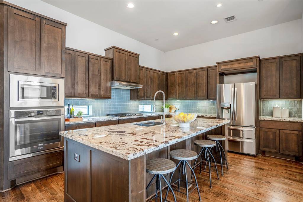 The kitchen features an expansive island located on the second floor with bar seating, granite counters, a 5-burner gas range, built-in microwave and oven. This is the perfect place to entertain. Designer touches include glass tile backsplash and under cabinet lighting.