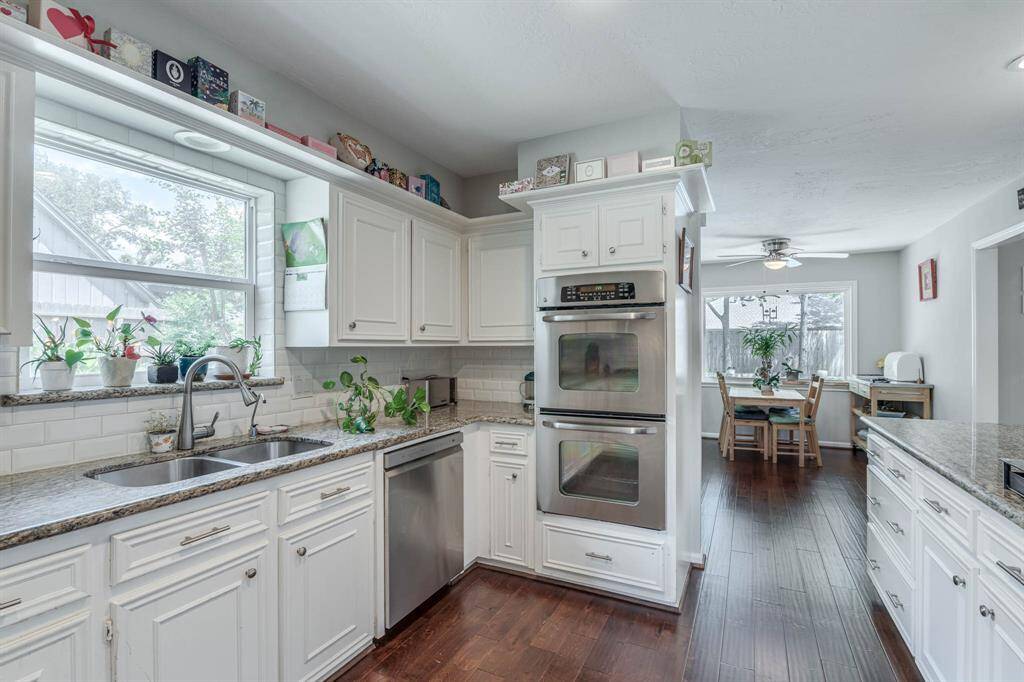 The chef-inspired kitchen boasts gleaming granite countertops, white cabinetry, and a sleek gas cooktop—perfect for both everyday meals and entertaining guests."