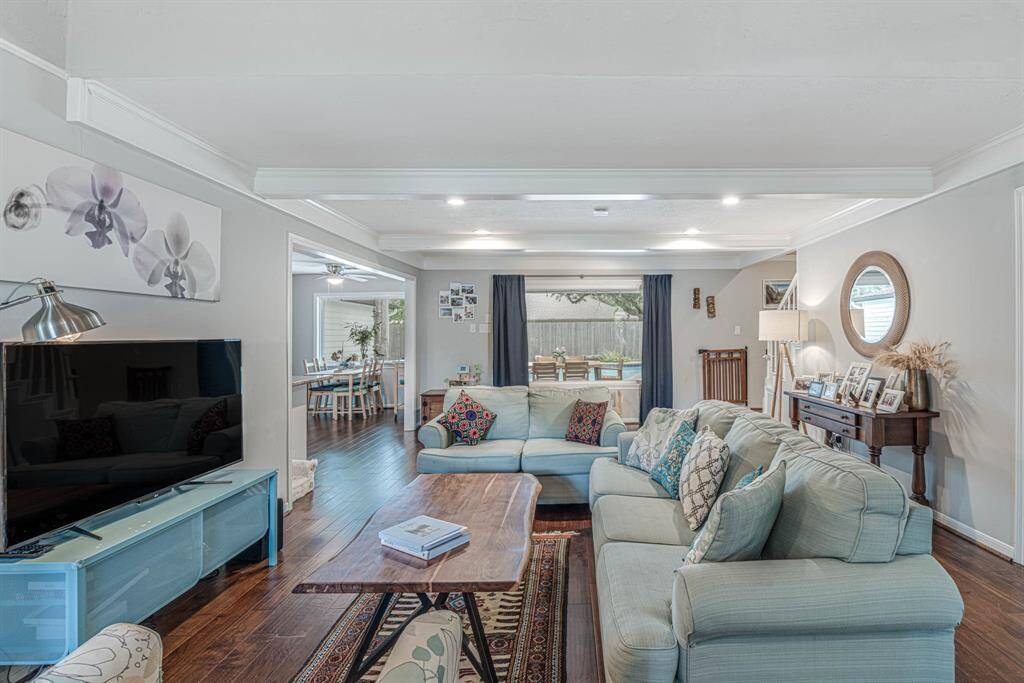 This living room offers generous space for relaxing and entertaining, with large windows that frame picturesque views of the sparkling pool.