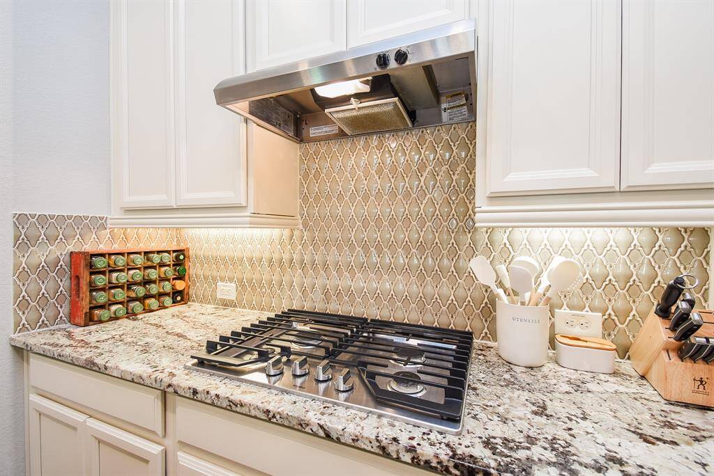 Gas cooktop  with overhead vent provides good ventilation while cooking. Pretty backsplash enhances the cabinetry.