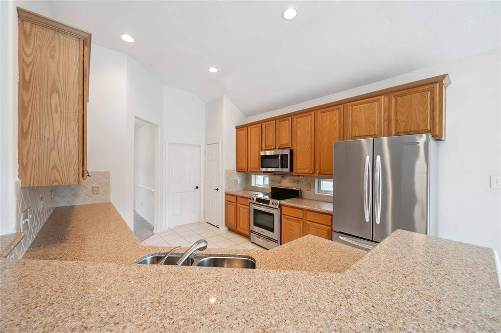 This kitchen features granite countertops, stainless steel appliances, and ample wooden cabinetry, creating a modern and functional space.