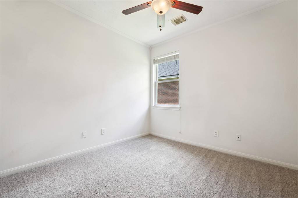 This room features soft carpet flooring, a ceiling fan, and a window providing natural light, creating a cozy and inviting space. Perfect for a bedroom or home office.