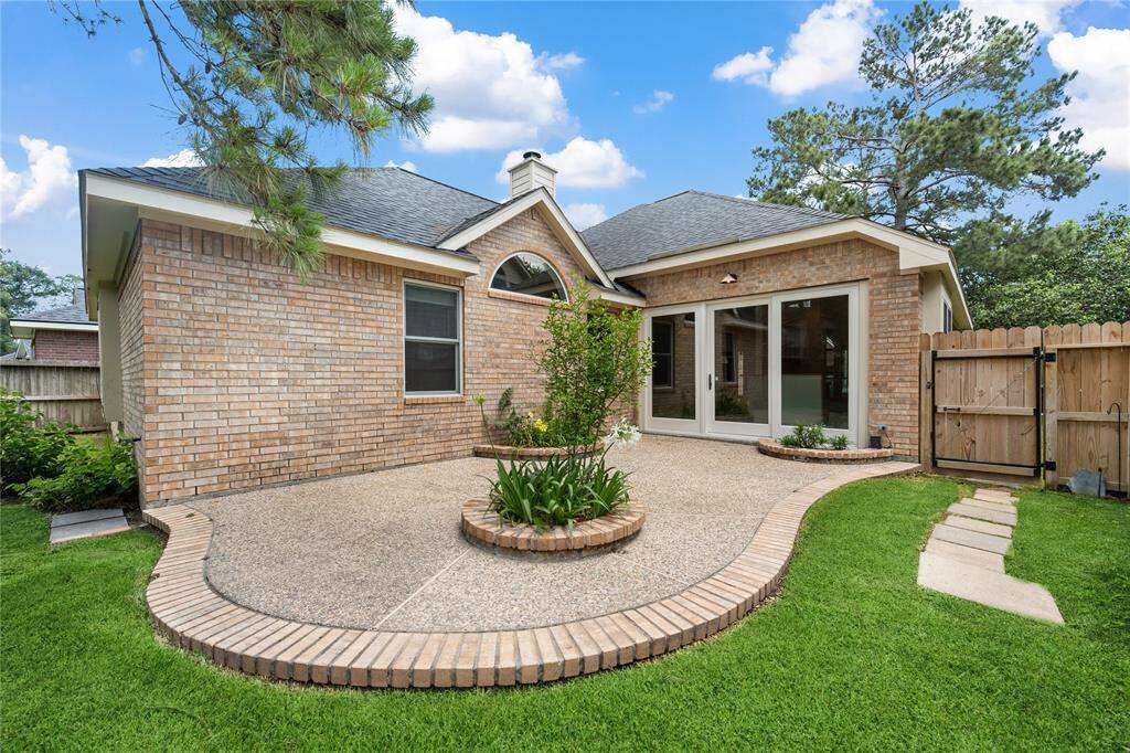 Charming backyard with a spacious patio, well-maintained brick exterior, and lush green lawn. Features a circular planter, sliding glass doors, and a wooden fence for privacy. Ideal for outdoor relaxation and entertaining.