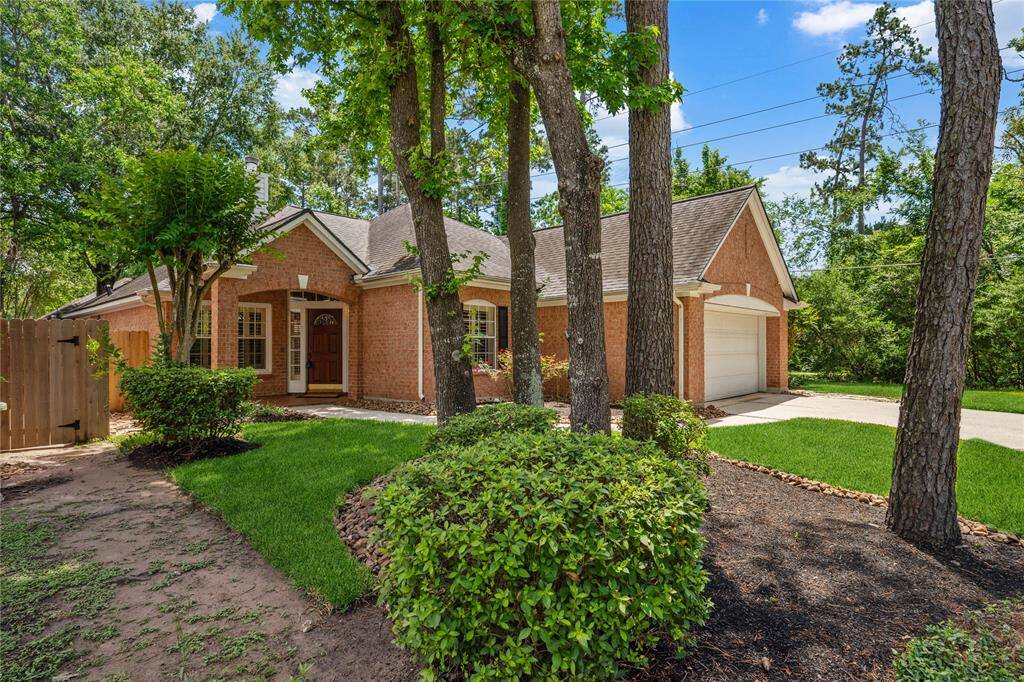 This charming brick home features a well-maintained front yard with lush greenery and mature trees. It includes a welcoming front porch and an attached garage, set against a backdrop of a serene wooded area and a greenbelt access.