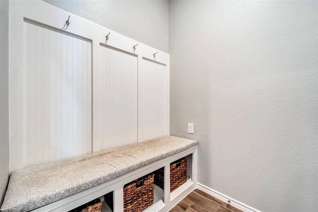 Mud room with cubbies and hooks near garage