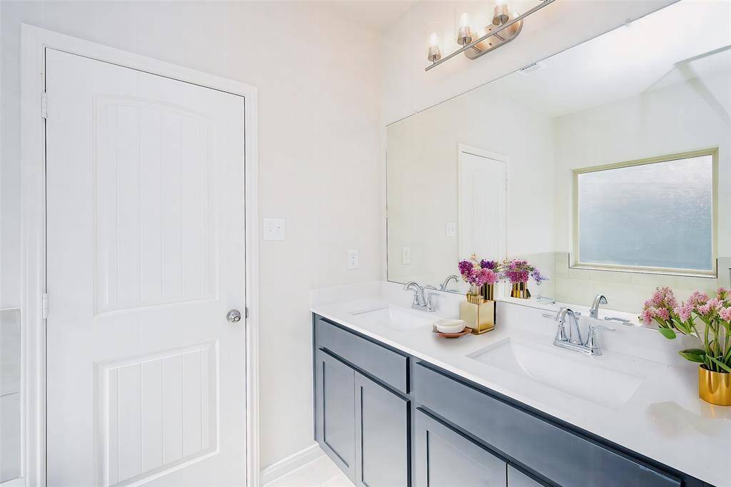 Comfortably generous dual sink console, wall-wide mirror and delicate lighting above offer relaxation and refreshment in this bath.