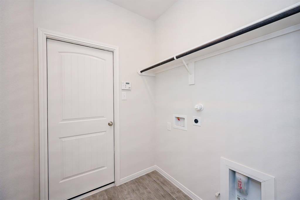 Even the spacious utility room is spotless and ready to receive laundry appliances, with a handy shelf, above.