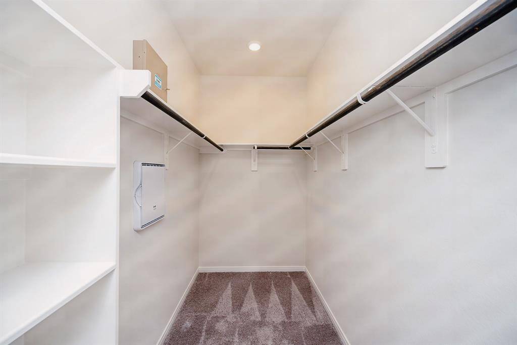 This marvelous carpeted primary walk-in closet welcomes any and all personal and storage items.