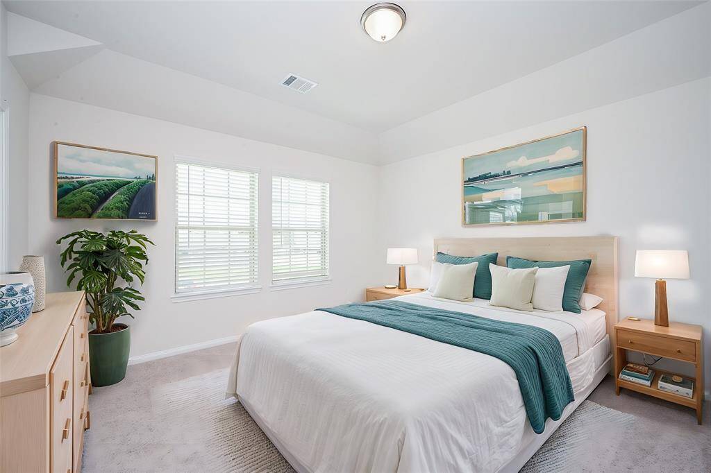 A bright, spacious bedroom welcomes sizeable pieces, under dual windows, spreading natural light.