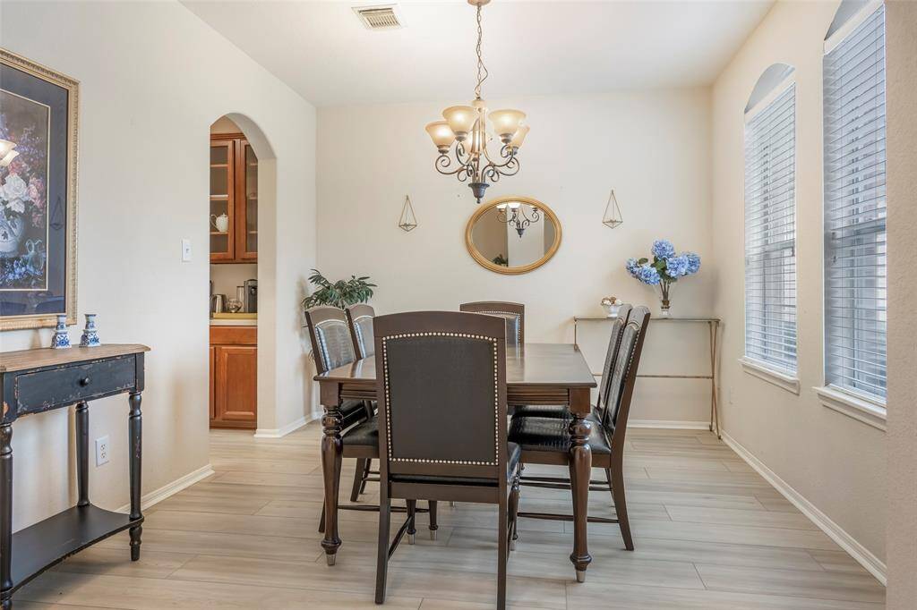 This dining room features a illuminated by a charming chandelier. Large windows provide ample natural light.  An archway leads to the kitchen, enhancing the room's flow.