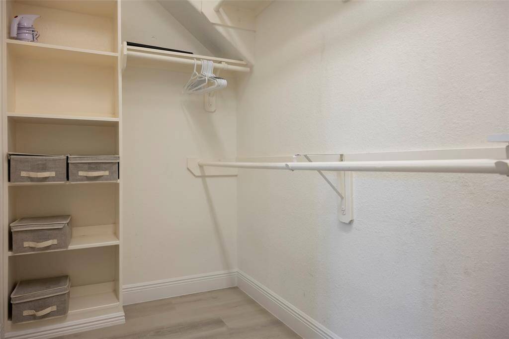 This photo shows a spacious walk-in closet with built-in shelves and hanging rods, perfect for organizing clothing and accessories.
