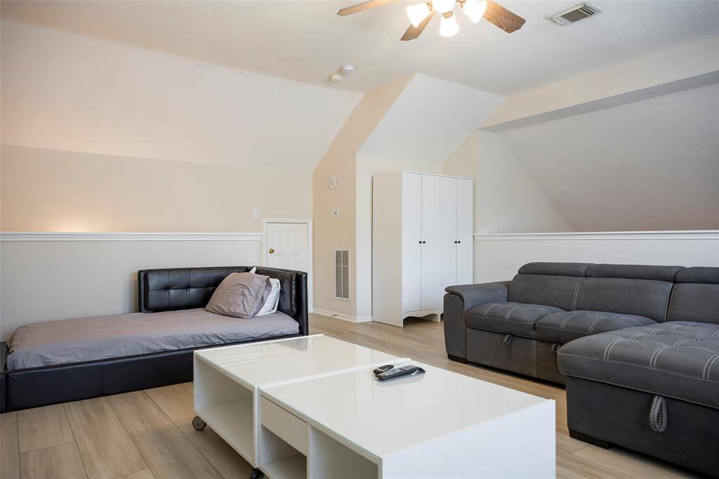 This spacious living area features a modern design with sleek hardwood floors, a cozy. The room is well-lit with a ceiling fan , ideal for relaxation or entertaining.