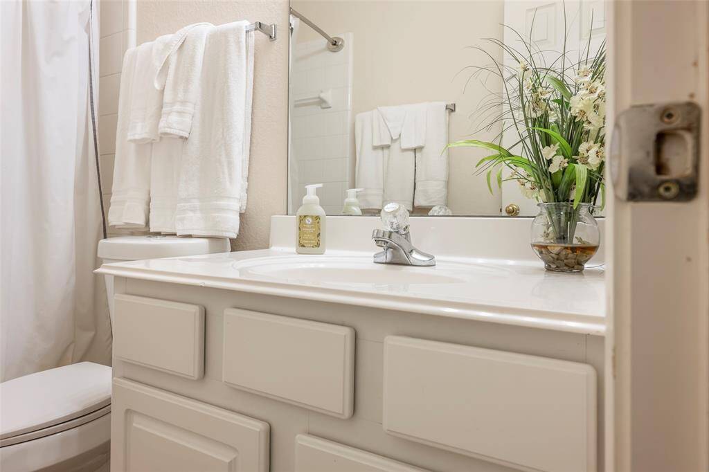 This photo showcases a clean, bright bathroom with a white vanity, a polished faucet.