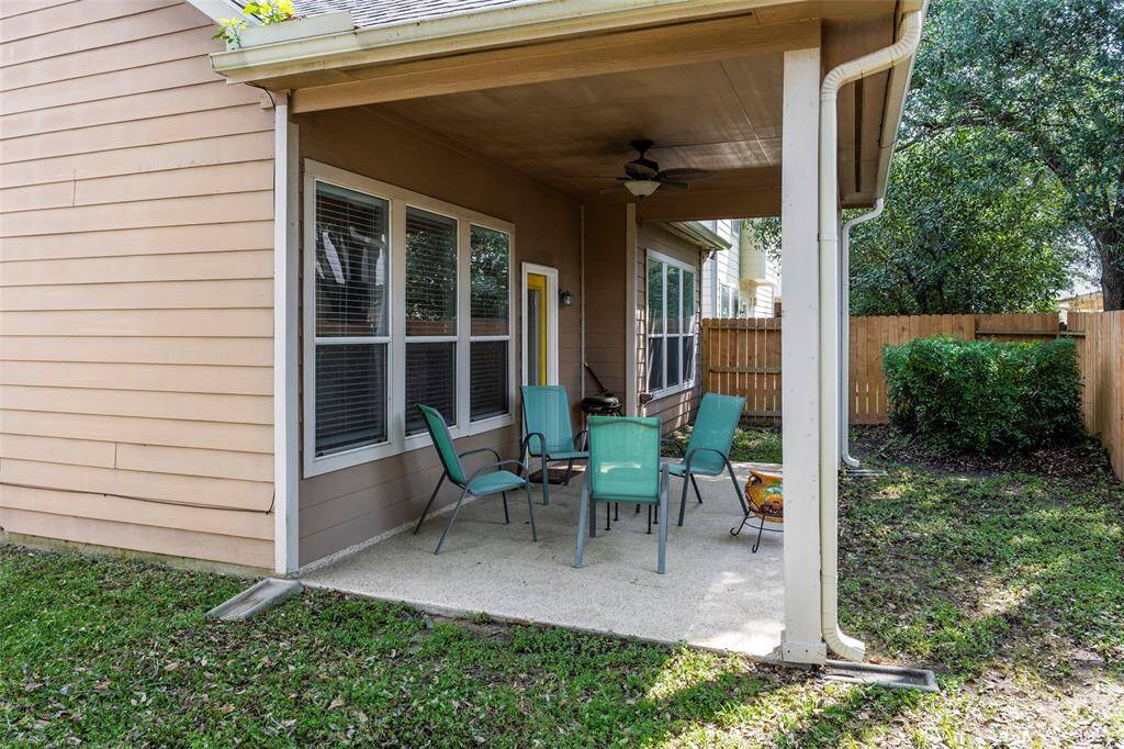 This inviting backyard features a covered patio area for entertaining. The space is surrounded by a fenced yard with lush greenery, providing privacy and a serene outdoor setting.