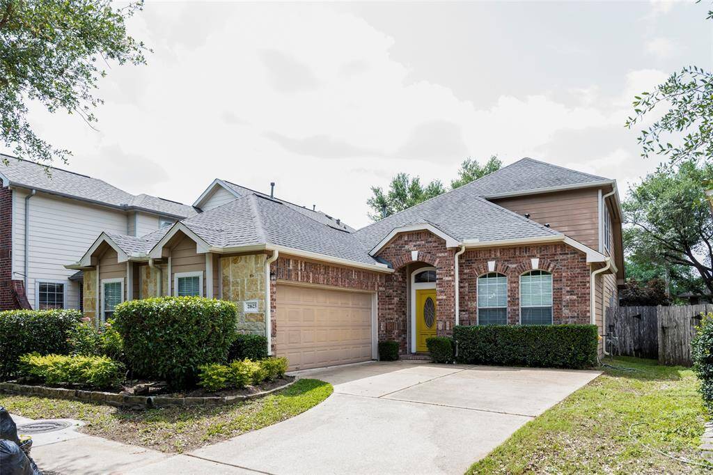 Charming home with a brick and stone exterior, featuring a tidy front yard, two-car garage, and a welcoming yellow front door. Located in a quiet neighborhood with mature trees.
