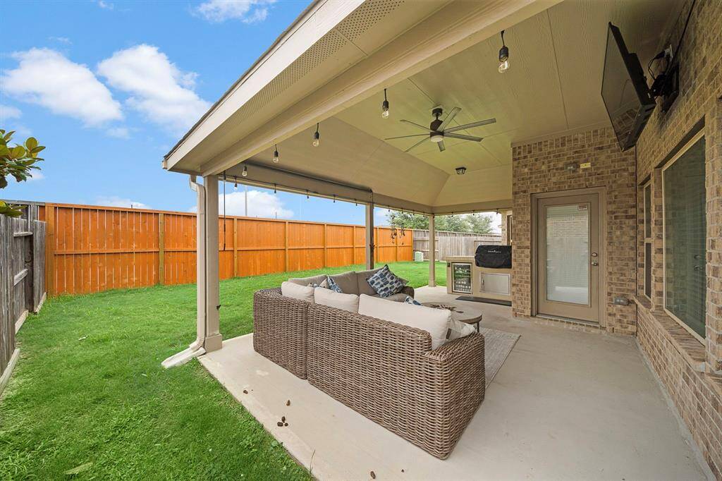 Spacious covered patio with a built-in kitchen, featuring a grill and refrigerator—perfect for outdoor entertaining.