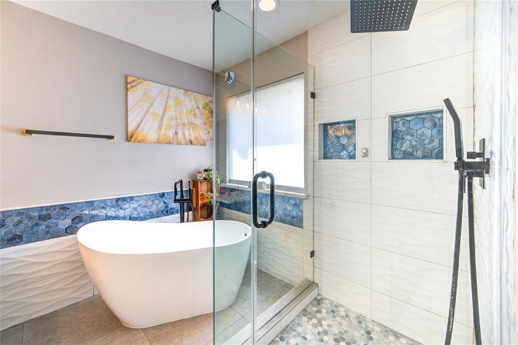This modern bathroom features a sleek freestanding tub, glass-enclosed shower with rainfall showerhead, and stylish hexagonal tile accents, creating a spa-like atmosphere.