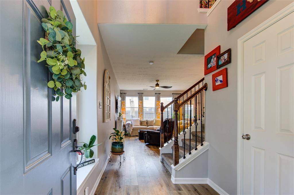 This inviting home features a welcoming entryway with stylish wood flooring and a decorative staircase. Natural light floods the open living area, creating a bright and cozy atmosphere ideal for relaxation.