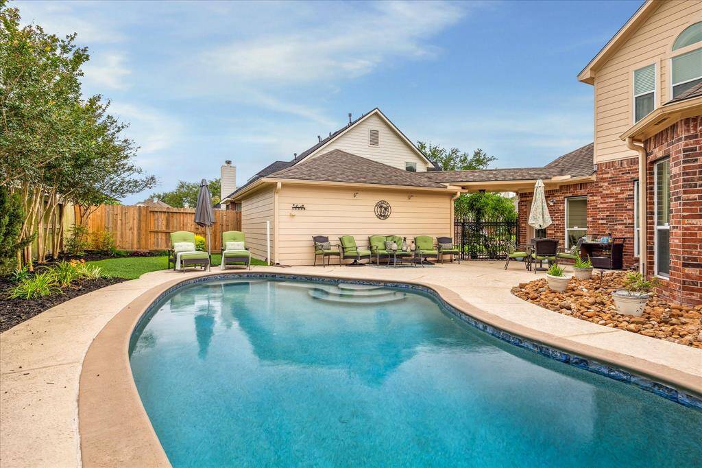 View of Backyard looking toward the Garage, Highlighting its Spacious Back Patio.  Beautiful Rod Iron Gate Adds even more Charm!!!  Bonus ~ All outside furniture remains!!!!  ***Don't Wait ~ Schedule Your Showing Now Before Its Gone***
