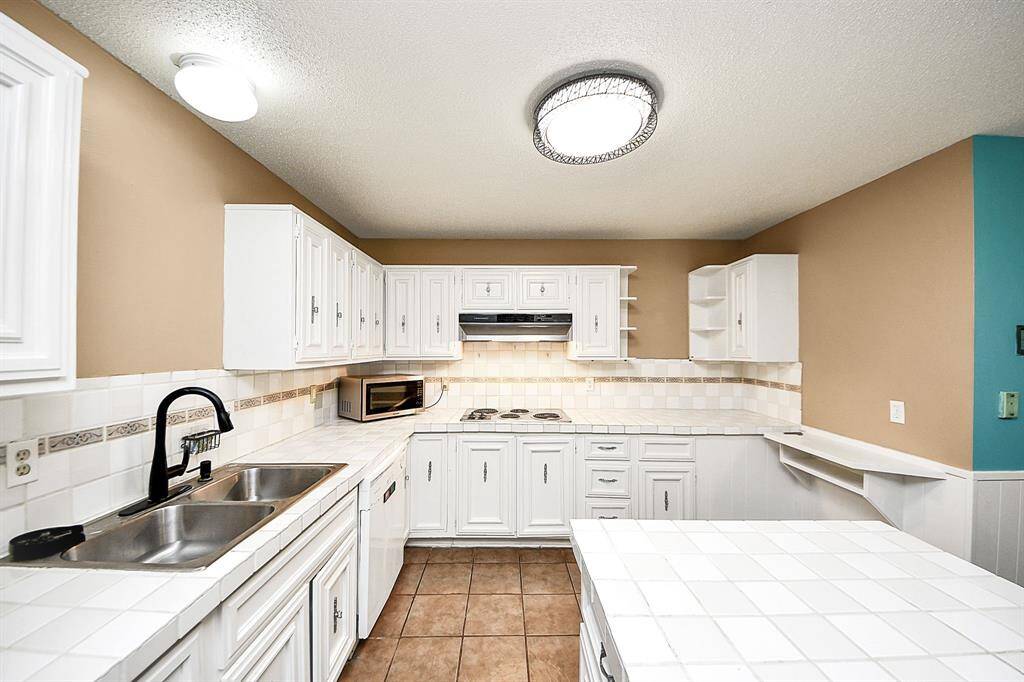 Kitchen - tile countertops & cabinetrySpacious kitchen with white tile countertops, ample cabinetry, and a functional layout designed for convenience and storage.