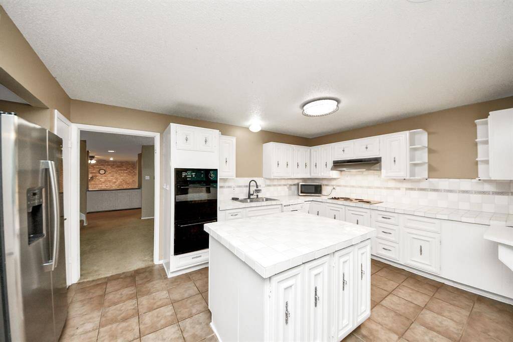 Kitchen view with laundry accessFull view of the kitchen island, double oven, stainless steel fridge, and direct access to the laundry nook and utility room.