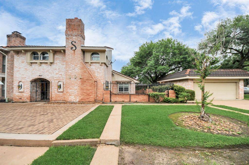 Side view with private gateSide entry with wrought iron gate adds character and privacy. The lush lawn and mature trees create a peaceful, inviting setting.